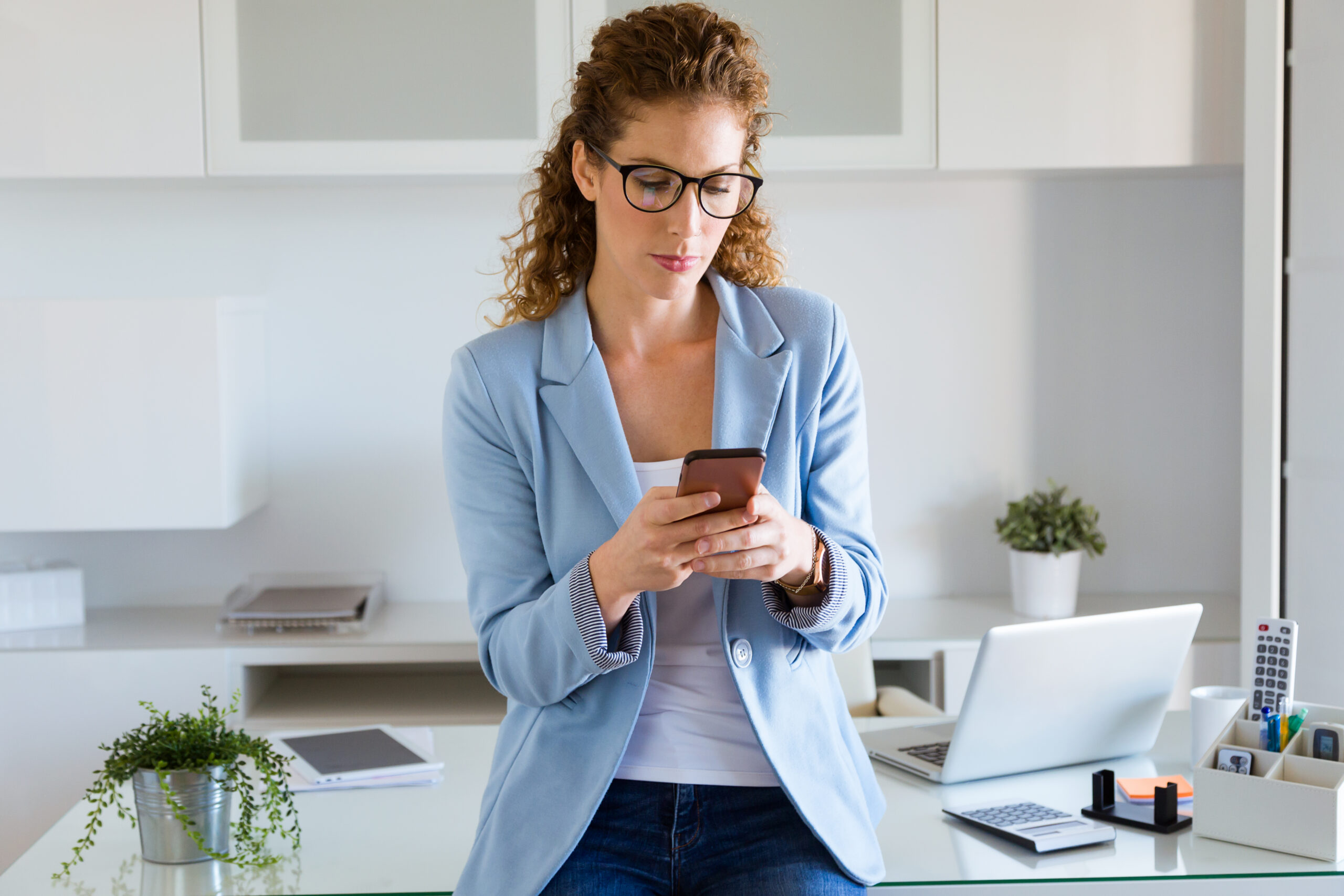 Portrait of beautiful young businesswoman using her mobile phone in the office.